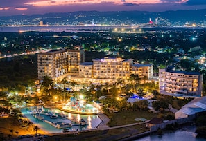 Un hôtel comprenant plusieurs bâtiments, une piscine et offrant une vue sur le paysage urbain la nuit.