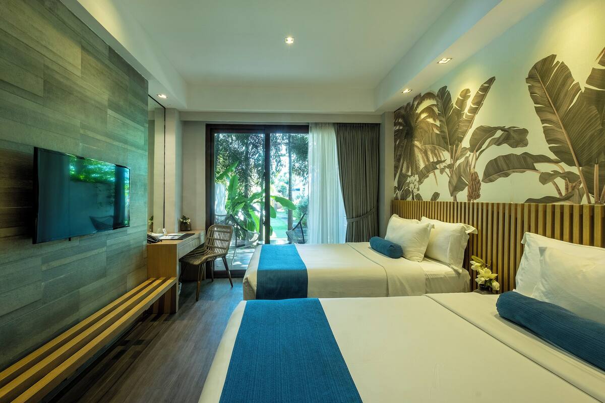 Habitación de hotel moderna con una cama grande, un escritorio, un televisor y vistas al exterior.