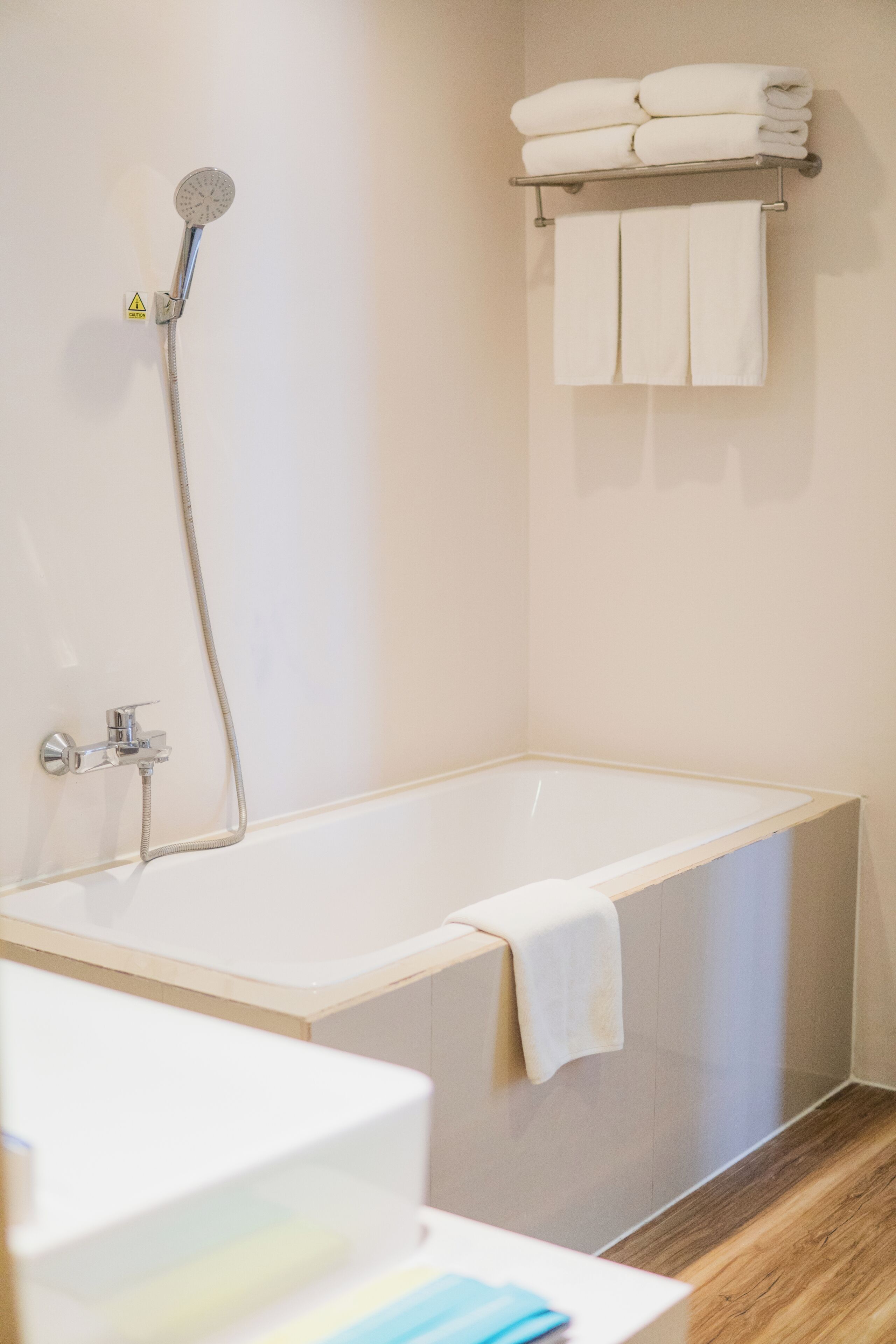 A modern bathroom with a bathtub, a showerhead, and a towel rack with folded towels.