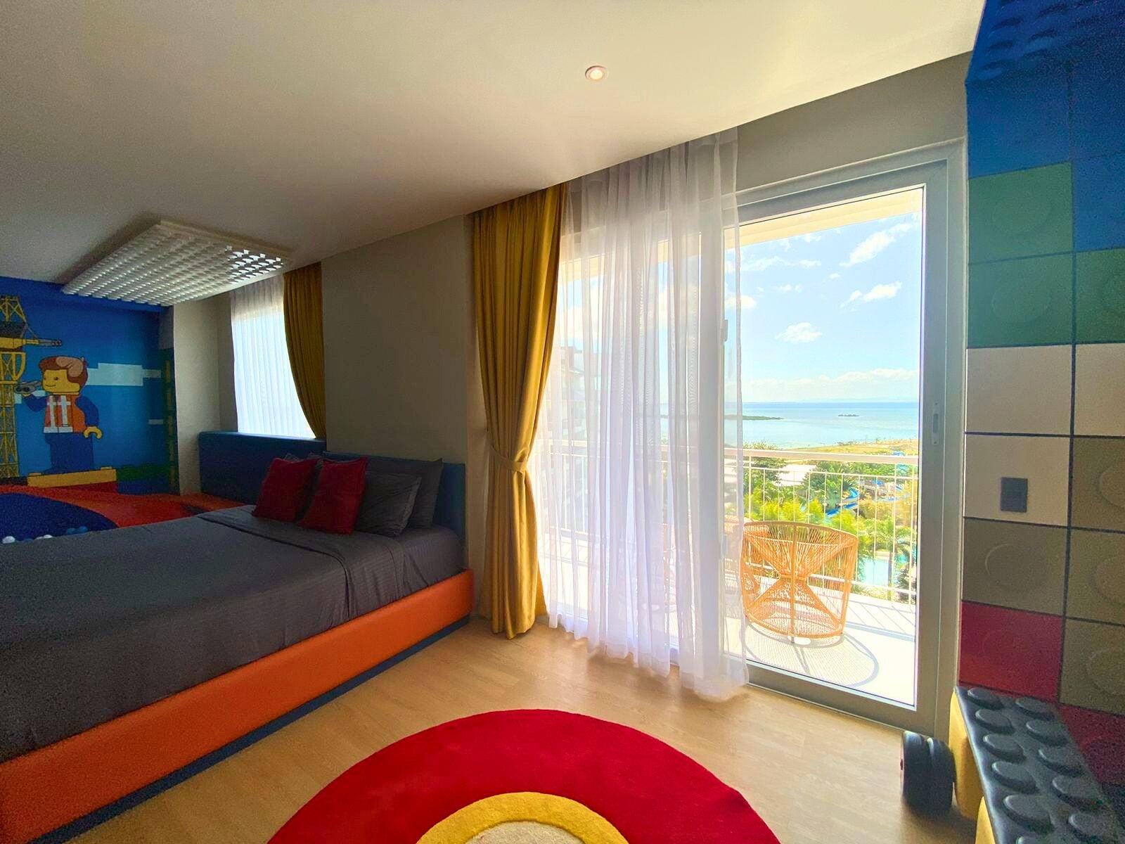 Habitación de hotel con cama, vista al mar y balcón con mobiliario exterior.