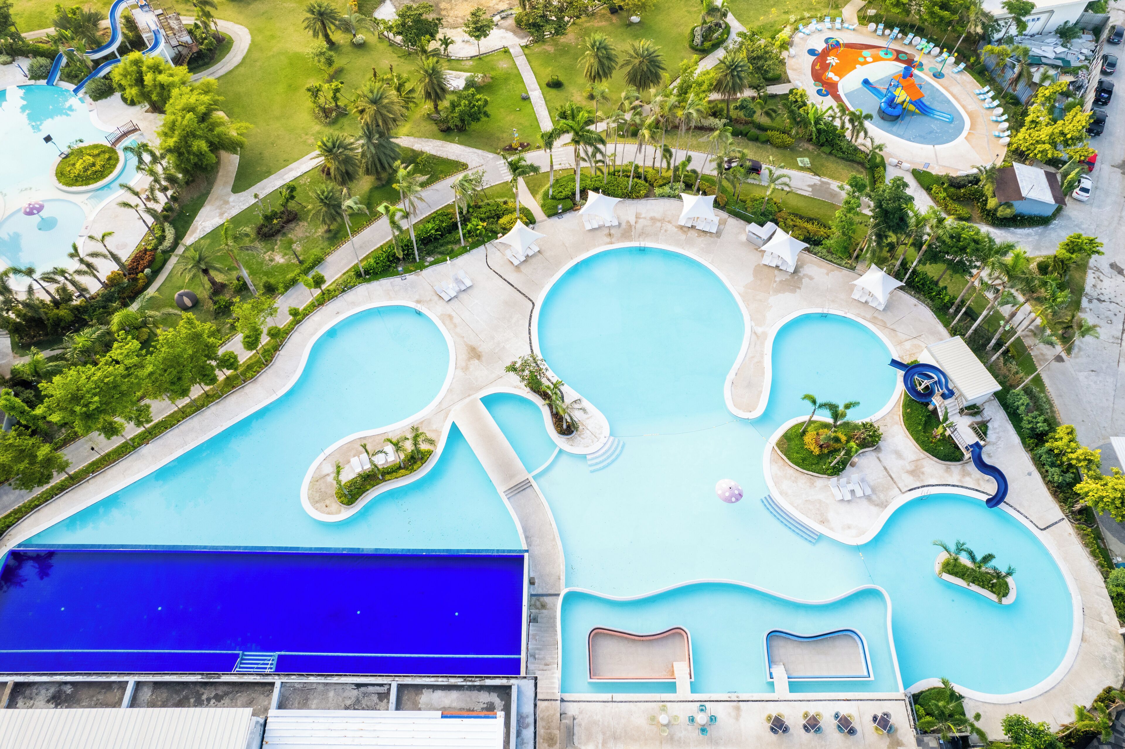 Vista aérea de un resort con varias piscinas, palmeras y zonas de descanso.
