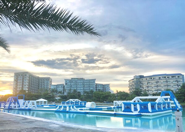 Une piscine avec des jeux gonflables, entourée d’immeubles d’habitation.