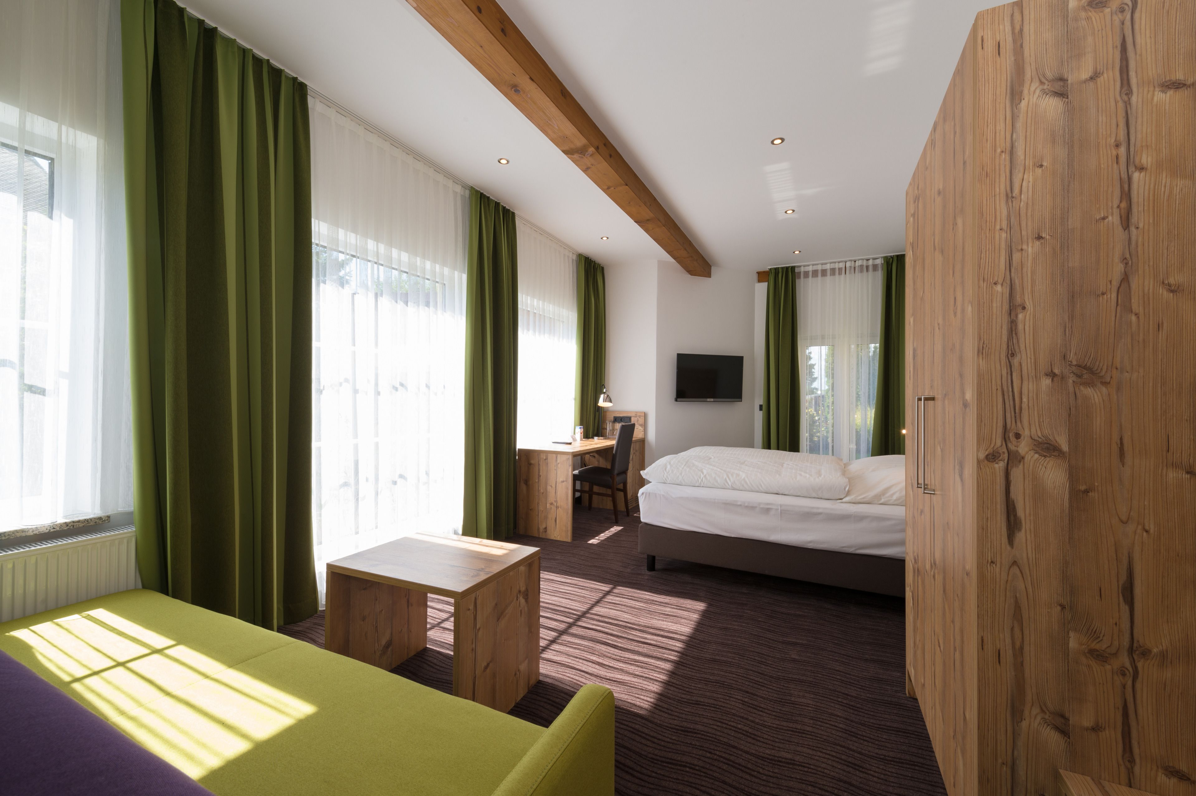 A hotel room with a bed, a desk, a chair, a small table, and a sofa.