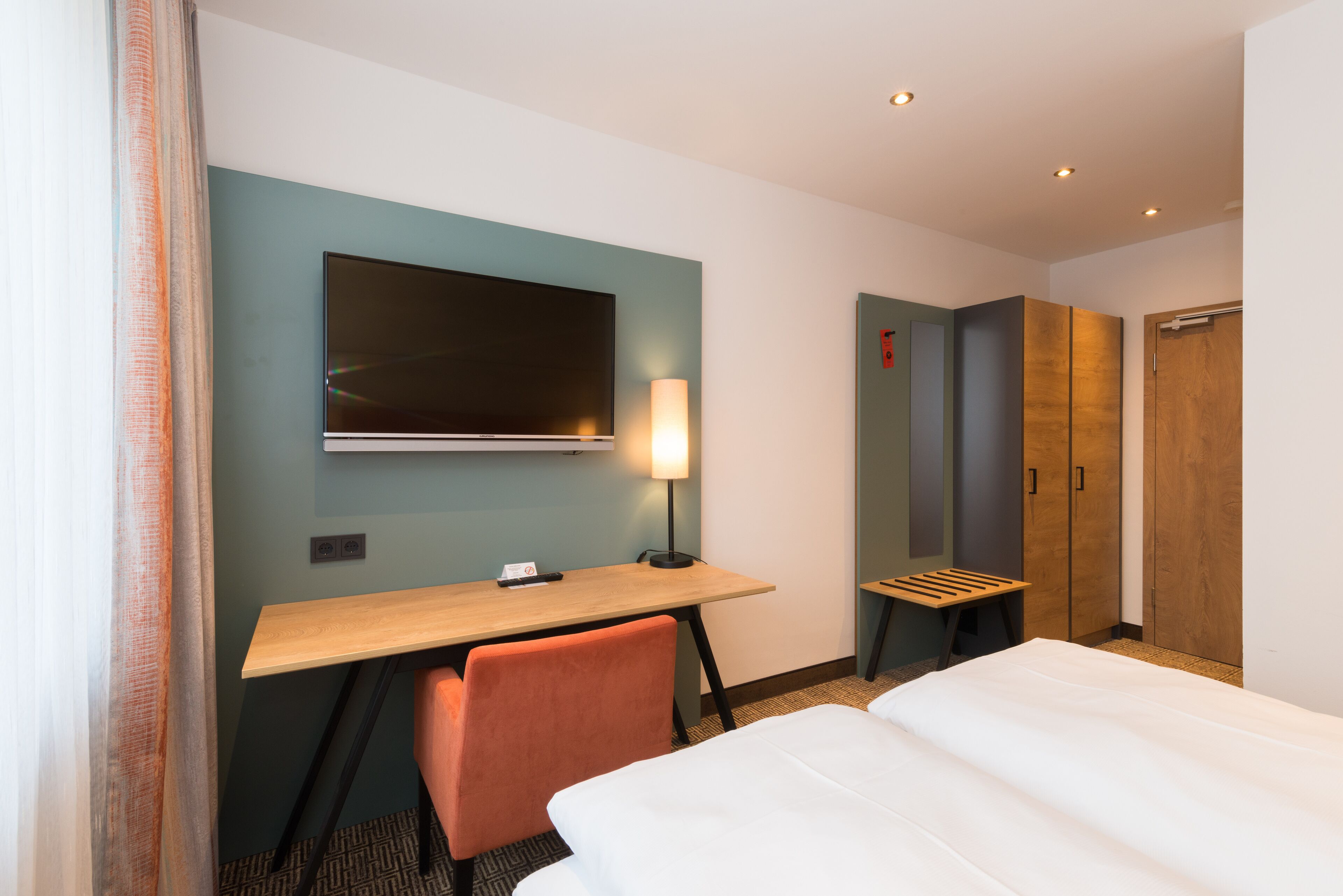 Une chambre d’hôtel équipée d’un lit, d’un bureau, d’une chaise, d’une télévision et d’une armoire.