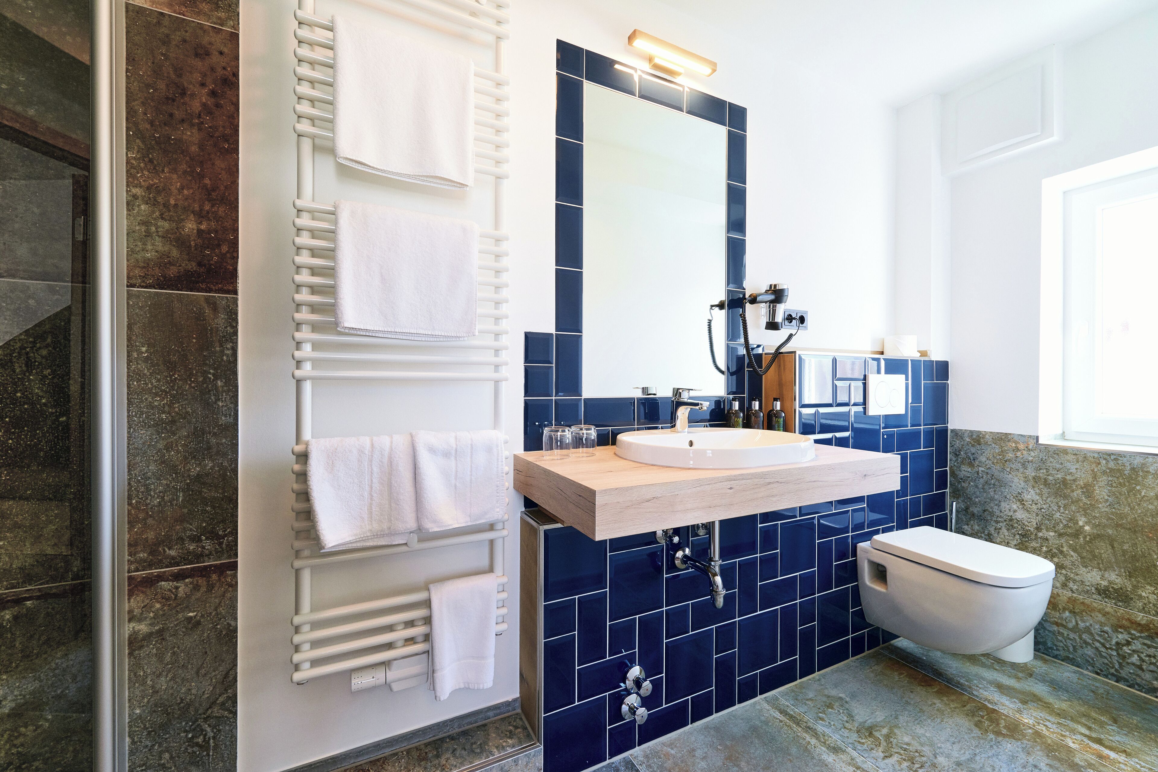 Een badkamer met een wit wastafel, blauwe tegels, een spiegel en een wit toilet.