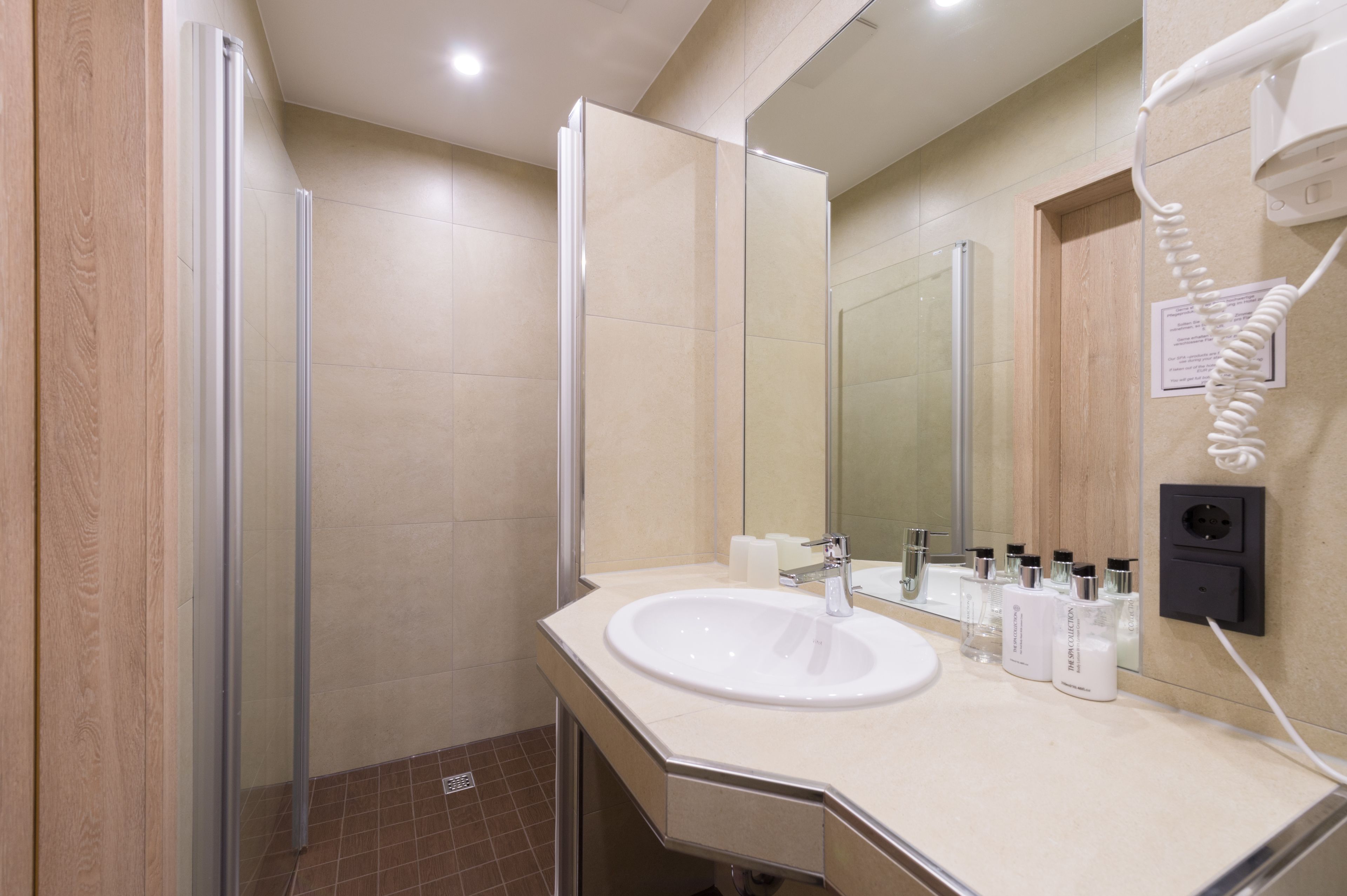 Une salle de bain moderne avec une douche à l’italienne en verre, un lavabo blanc et un miroir.