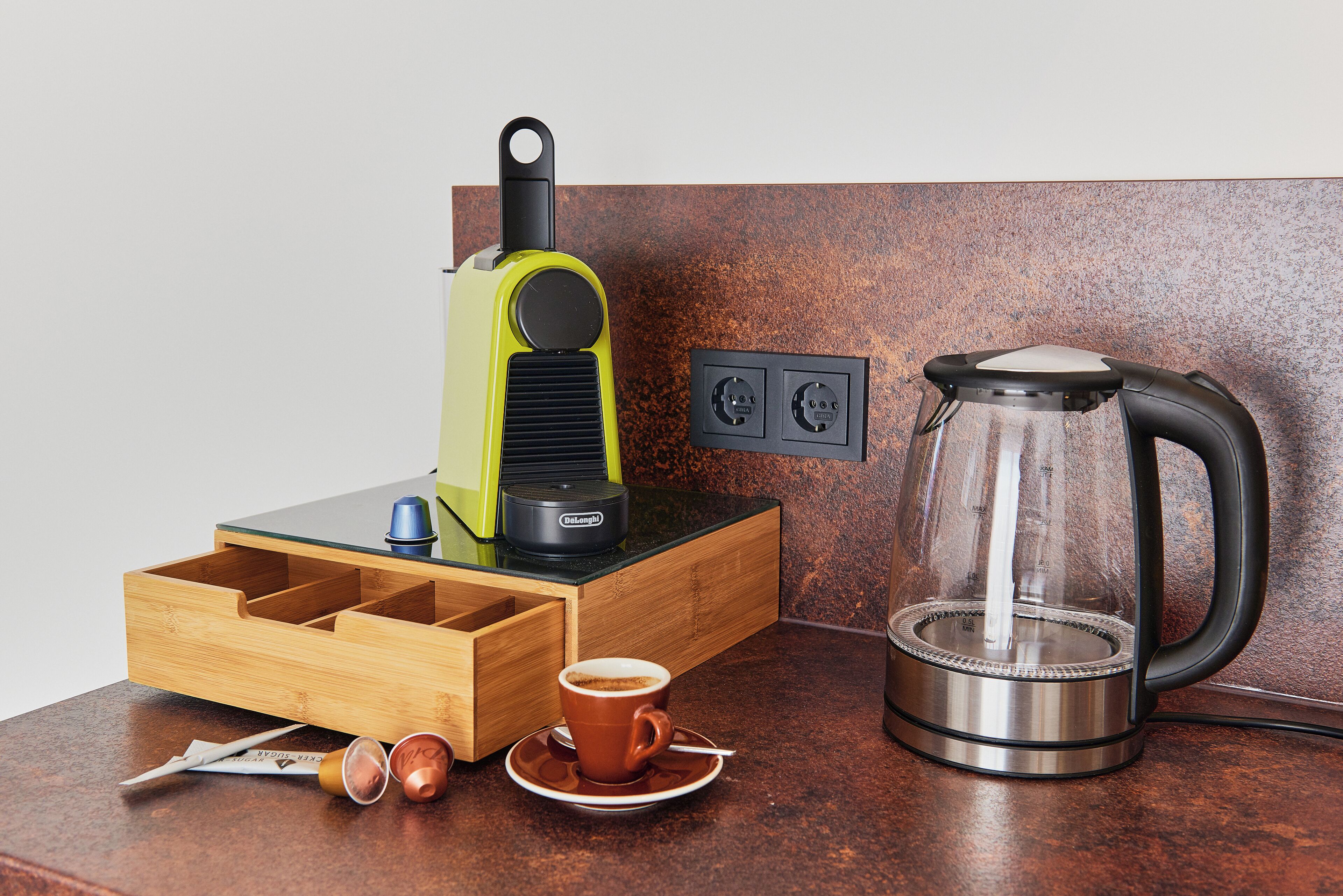 Eine Küchenarbeitsplatte mit Kaffeemaschine, Wasserkocher, einer Schubladenordnung und einer Kaffeetasse.