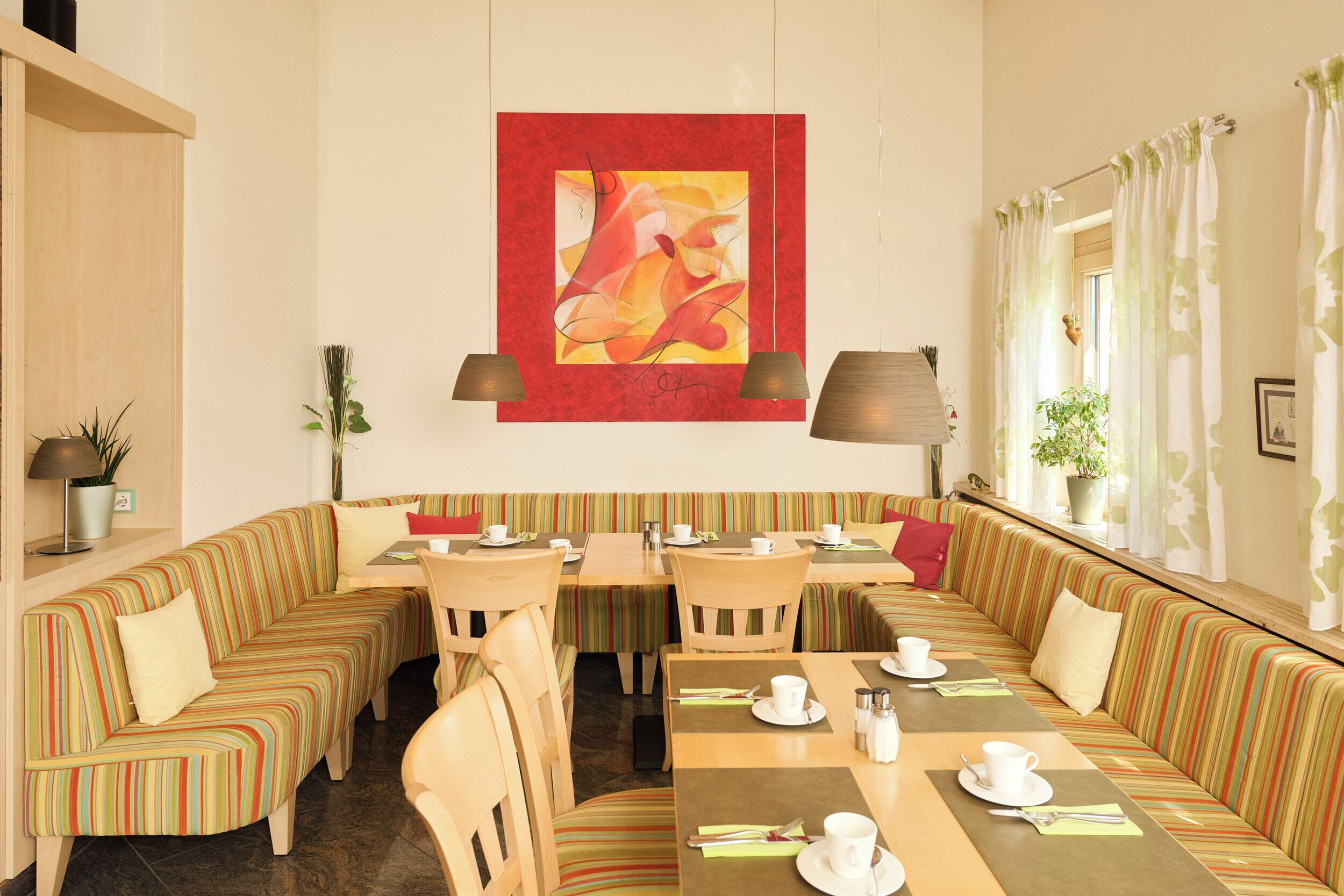 A hotel dining area with striped sofas, tables, and chairs.