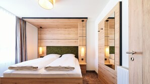 Un dormitorio moderno con una cama de madera, lámparas de noche y un espejo grande.