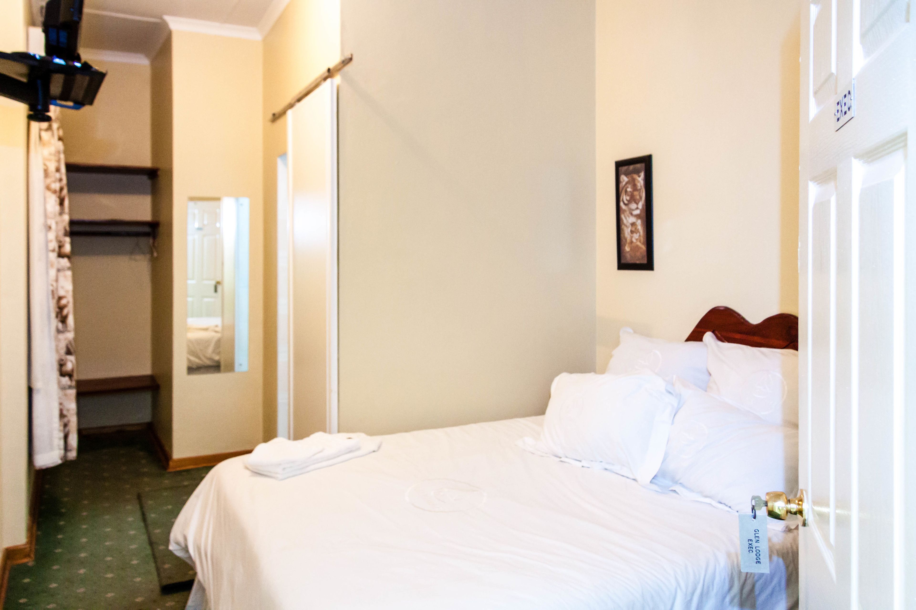 Une chambre d’hôtel avec un lit bien fait, une table de chevet, un miroir et une porte dotée d’un système de verrouillage à carte magnétique.