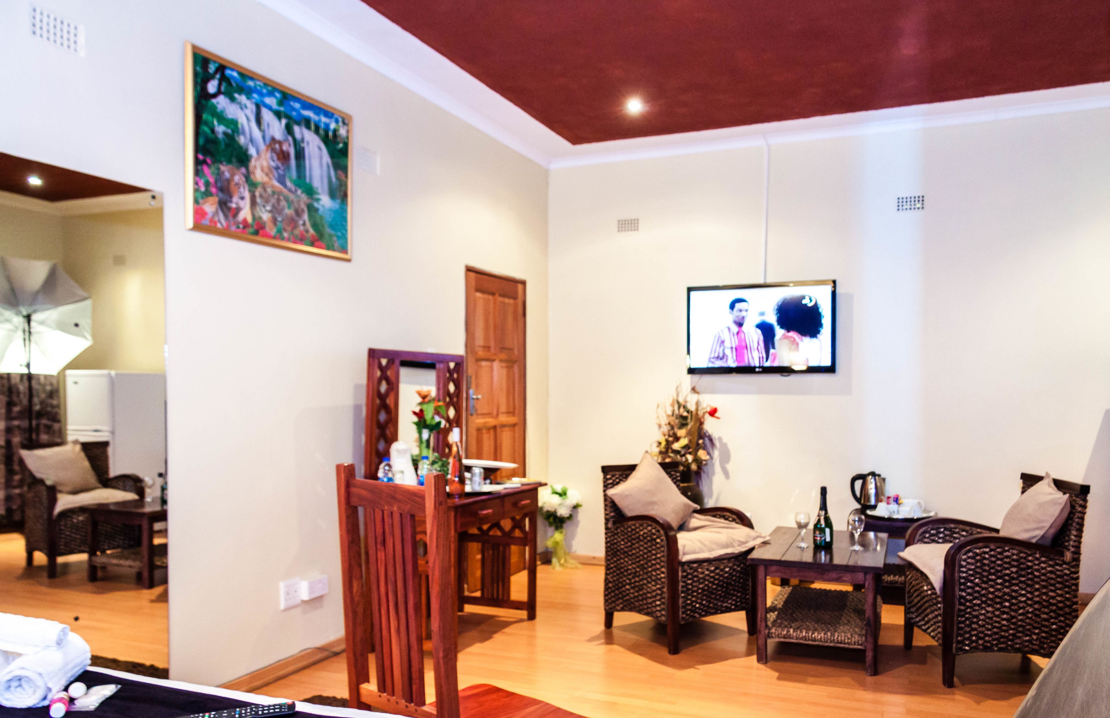 A living room with a television, wicker furniture, a dining table, and a painting on the wall.