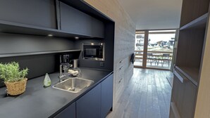 A modern kitchen with a built-in microwave, a sink, and a small potted plant. - alpen select apartments Kleinwalsertal (Mittelberg)