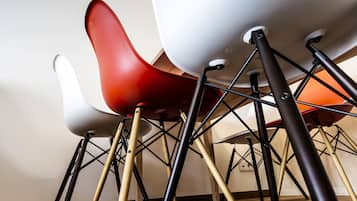 Ein Detailaufnahme eines modernen Stuhls mit markantem Design, der Weiß und Rot kombiniert und einen Metallrahmen mit Holzbeinen aufweist.