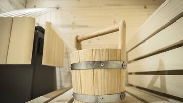A wooden barrel with metal bands and a handle, placed on a bench in a wooden interior.