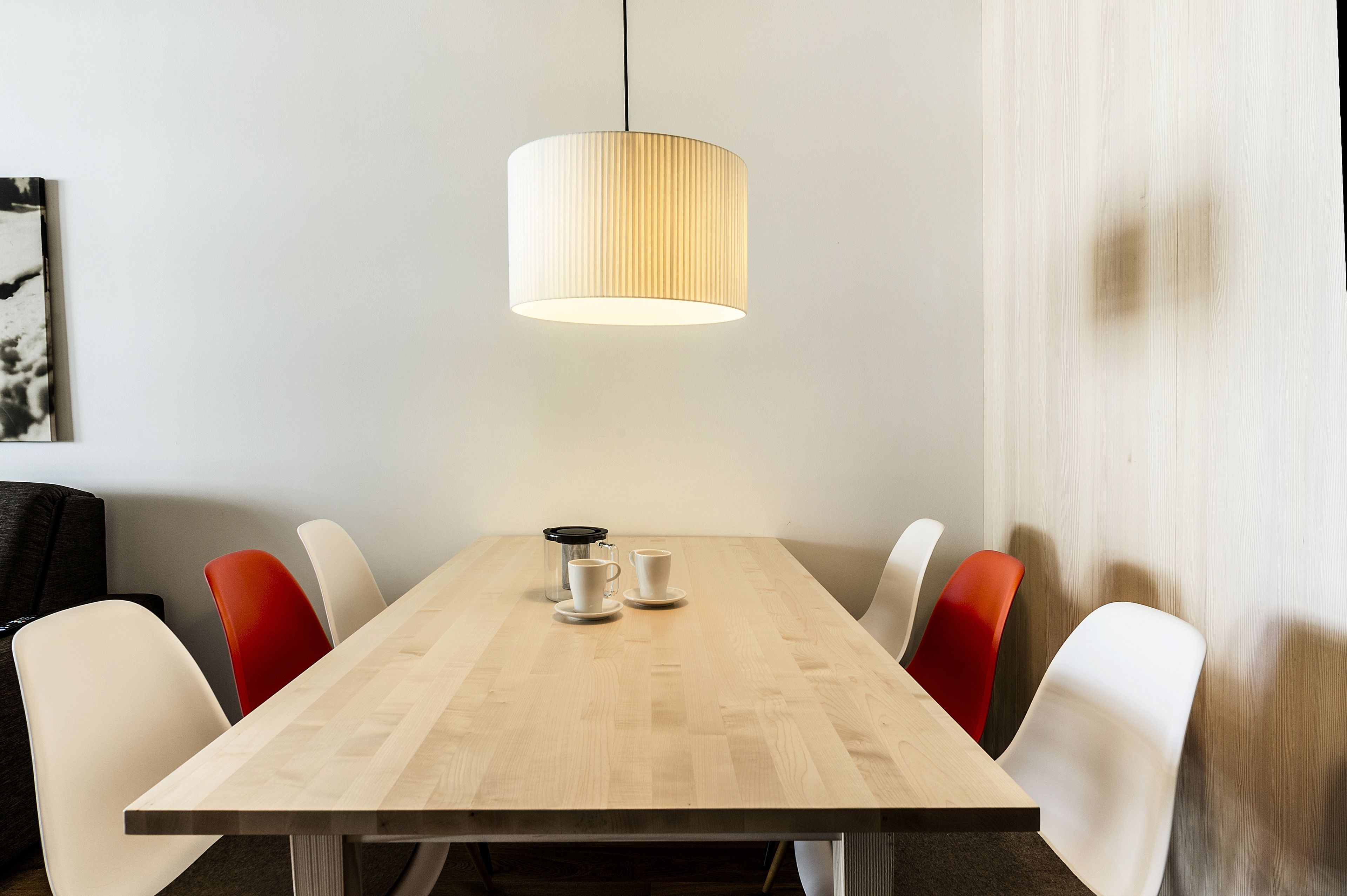 A conference table with a coffee maker, cups, and chairs.