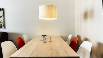 A conference table with a coffee maker, cups, and chairs.