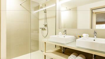 Un bagno moderno con cabina doccia in vetro, due lavabi e uno specchio grande.