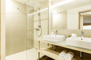 A modern bathroom with a glass shower enclosure, two sinks, and a large mirror. - alpen select apartments Kleinwalsertal (Mittelberg)