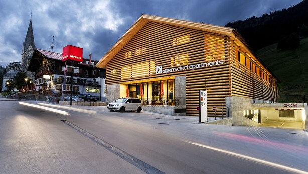 A building with a sloped roof and wooden facade, labeled 'open select partnerships'. - alpen select apartments Kleinwalsertal (Mittelberg)