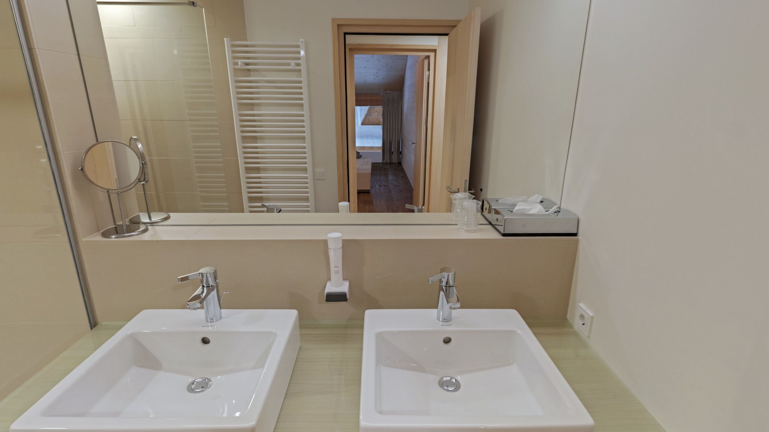 A bathroom with two sinks, a mirror, and a towel rack.