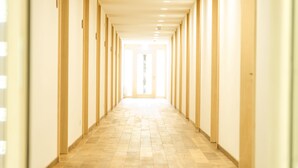 A long, narrow hallway with wooden floors and walls, leading to a bright exit. - alpen select apartments Kleinwalsertal (Mittelberg)