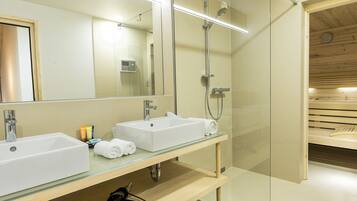 Un bagno moderno con due lavandini, cabina doccia in vetro e una panca in legno.