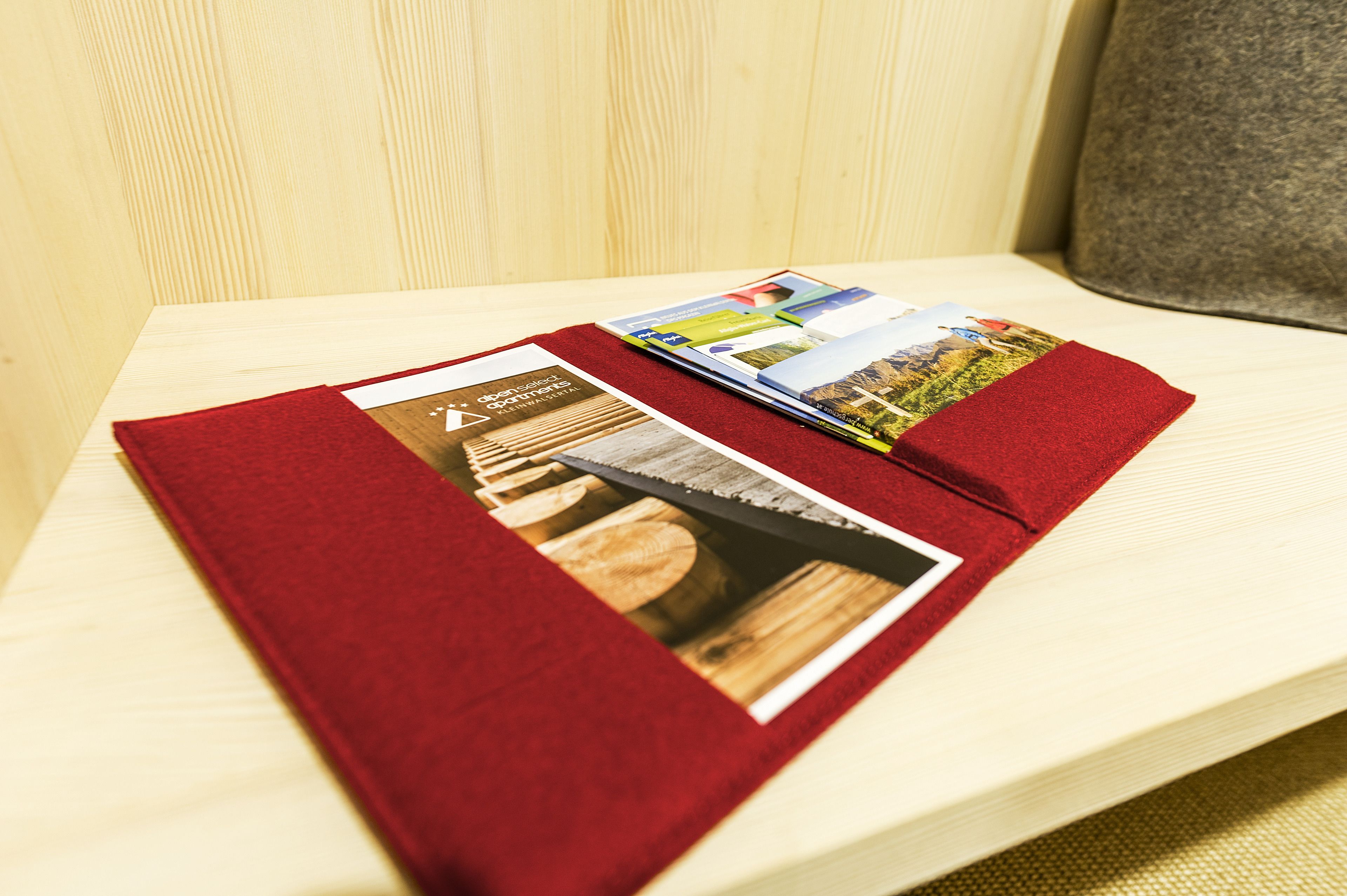 Een houten tafel met een rode map vol folders.