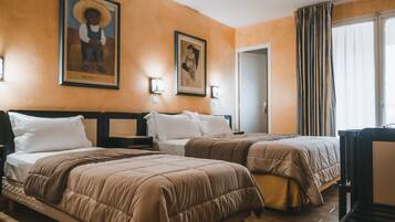 Habitación de hotel con dos camas, un cuadro grande en la pared y una ventana con cortinas.