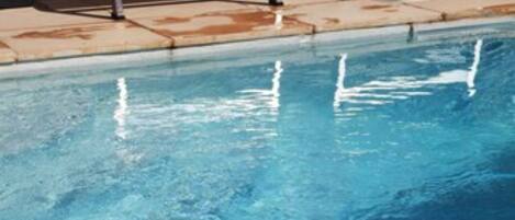 Una piscina con sillas de descanso y un suelo de hormigón.