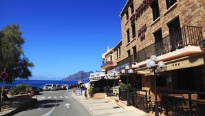 A hotel with a stone facade, outdoor seating, and a view of the sea. - Hôtel le Subrini (Ota)