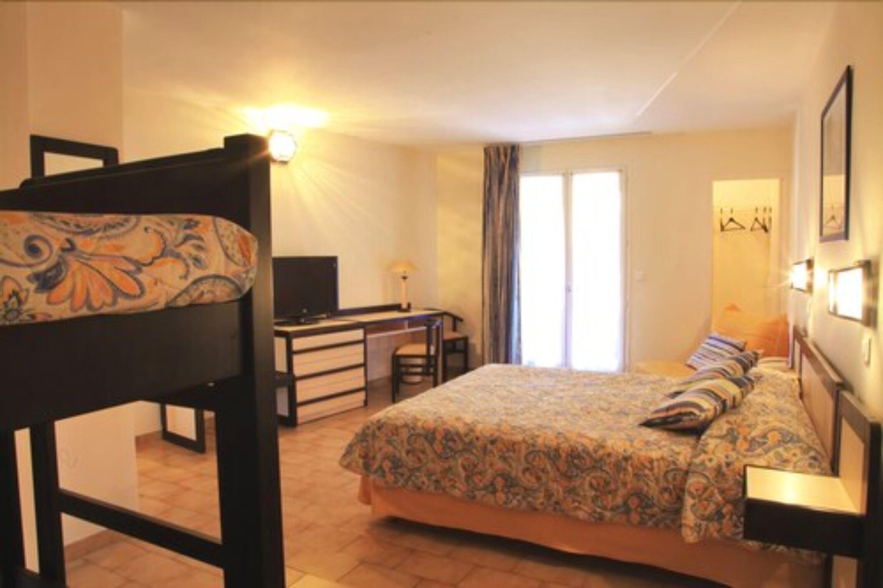 Ein Schlafzimmer mit einem Bett, einem Schreibtisch, einem Sessel und einem Fernseher.
