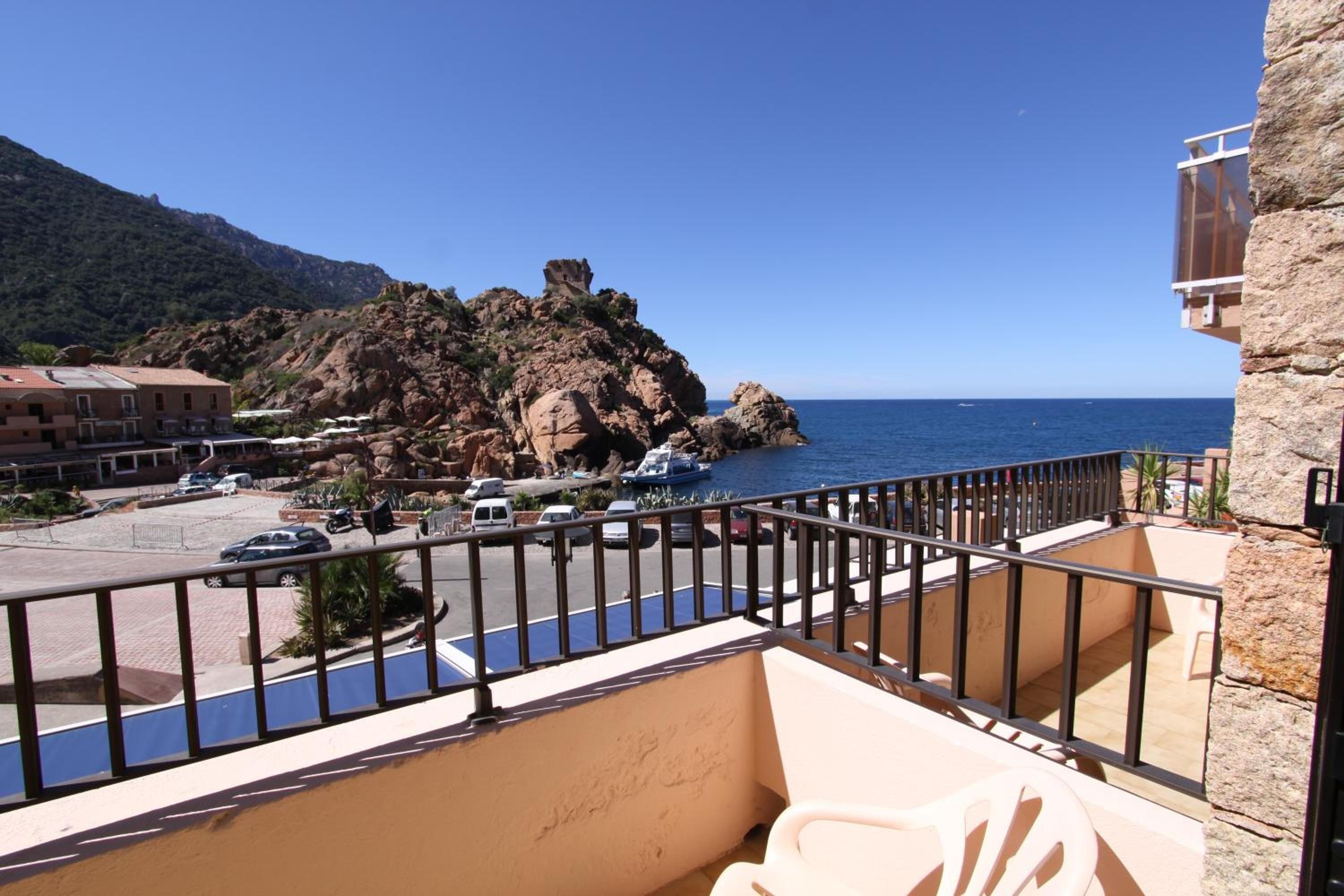 Un balcon donnant sur la mer, une colline rocheuse et un bâtiment doté d’un balcon.