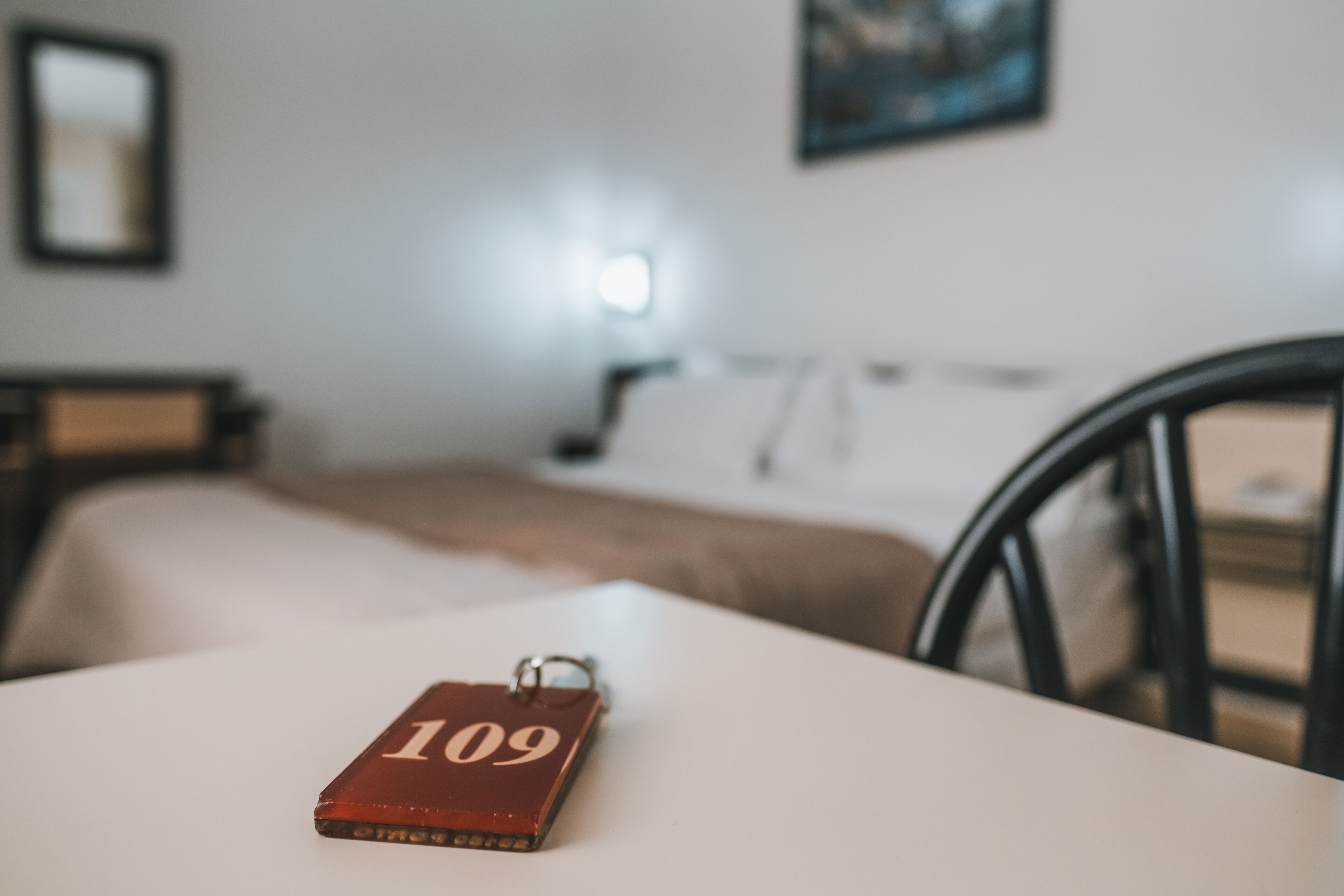 Un llavero con el número 109 sobre una mesa blanca en una habitación con cama y silla.