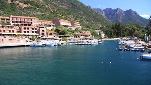 A marina with boats docked, a bridge, and buildings with balconies overlooking the water. - Hôtel le Subrini (Ota)