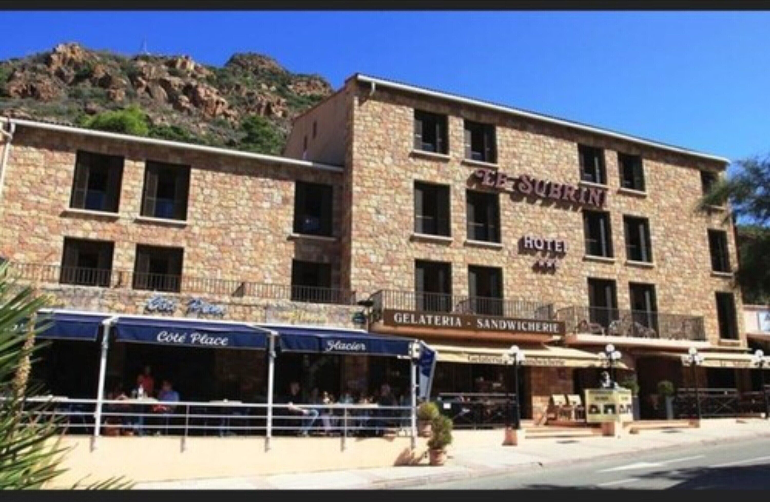 A hotel with a stone facade, multiple windows, and outdoor seating areas.