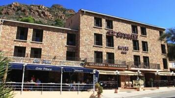 A hotel with a stone facade, multiple windows, and outdoor seating areas.