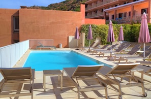 Piscine extérieure en saison, parasols, chaises longues