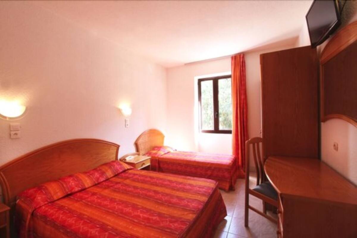 A room with two beds, a desk, a chair, and a television.