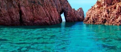 A coastal scene with clear turquoise water and rocky cliffs.