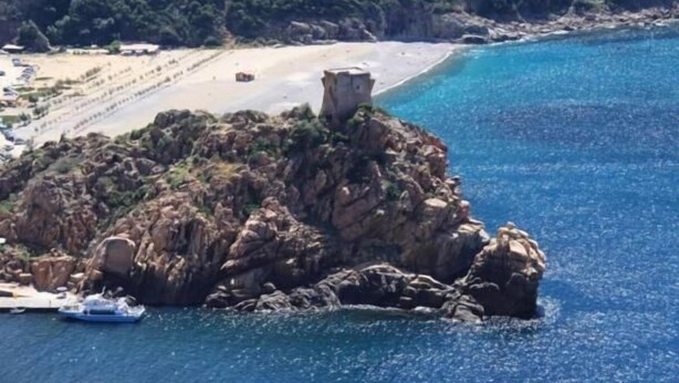 A rocky island with a tower, surrounded by clear blue water and a sandy beach. - Hôtel Idéal (Ota)