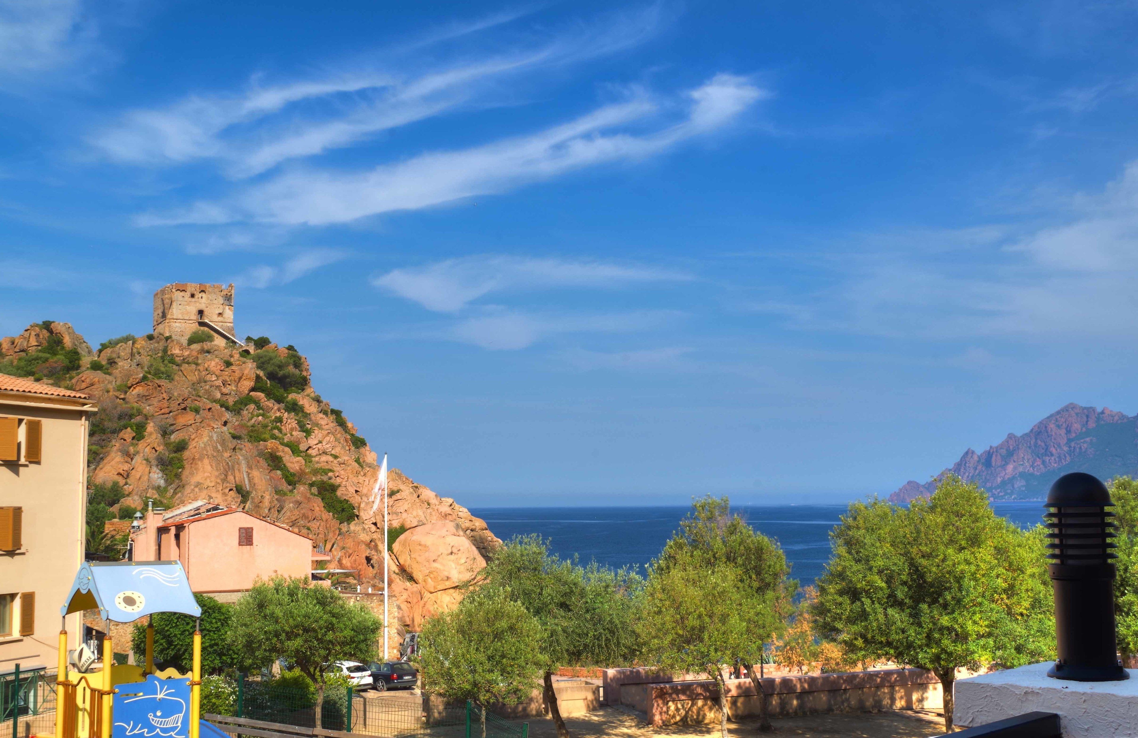 Une ville côtière avec un château historique perché sur une colline, une aire de jeux et une vue sur la mer.