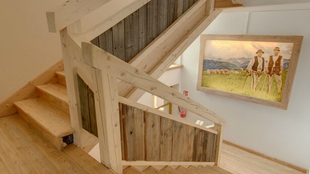 Eine Holztreppe mit rustikalem Design, die zu einer oberen Etage führt.