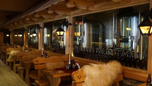 Ein Restaurant mit Holztischen, einer mit Fell bezogenen Bank und Flaschen auf der Theke.