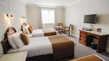 Habitación de hotel con dos camas, un escritorio, una silla, un televisor y una ventana con cortinas.