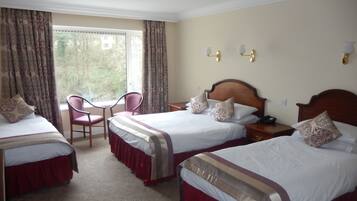 A hotel room with two beds, a chair, a desk, and a window with curtains.