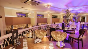Un restaurante con mostrador curvo, asientos acolchados e iluminación colgante.