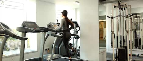Ein Fitnessstudio mit Laufbändern, Kraftgeräten und einem Spiegel.