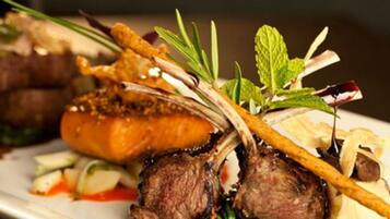 A plated dish with meat, vegetables, and garnishes.