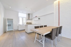 A modern kitchen with white cabinetry, a wooden dining table, and four chairs. - Brederode Area Apartments (Antwerp)