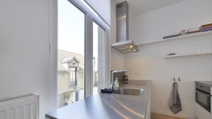 Una cucina moderna con un piano di lavoro in acciaio inossidabile, forno integrato e finestra che si affaccia su una zona residenziale.
